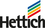 Das Hettich-Logo zeigt den Schriftzug Hettich in fetten schwarzen Buchstaben mit vier diagonalen Linien darüber in den Farben Blau, Grün, Gelb und Rot.